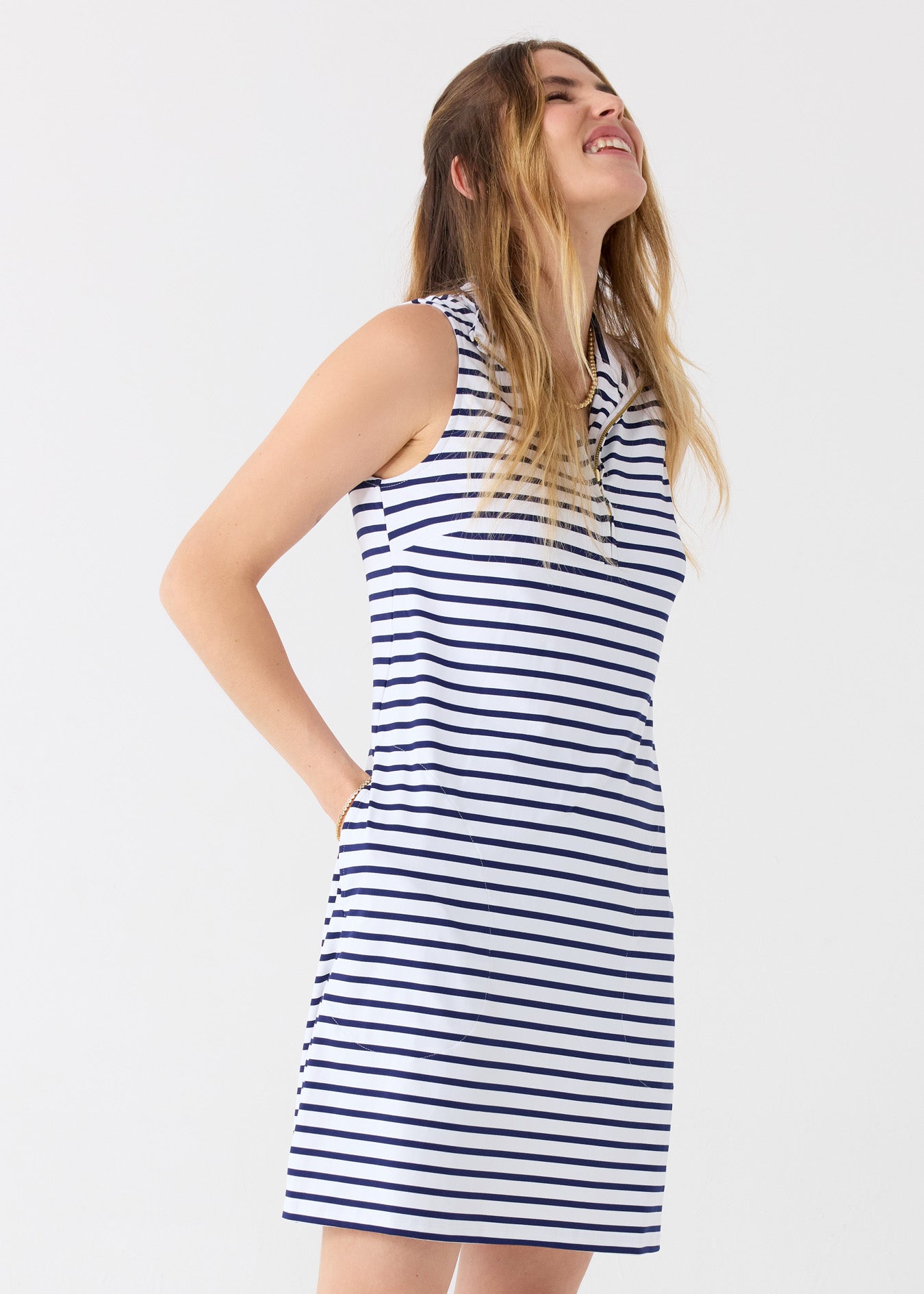 A blonde woman wearing the Cabana Life sun protective Navy Stripe 1/4 Zip Sleeveless Sport Dress with a hand in her pocket.