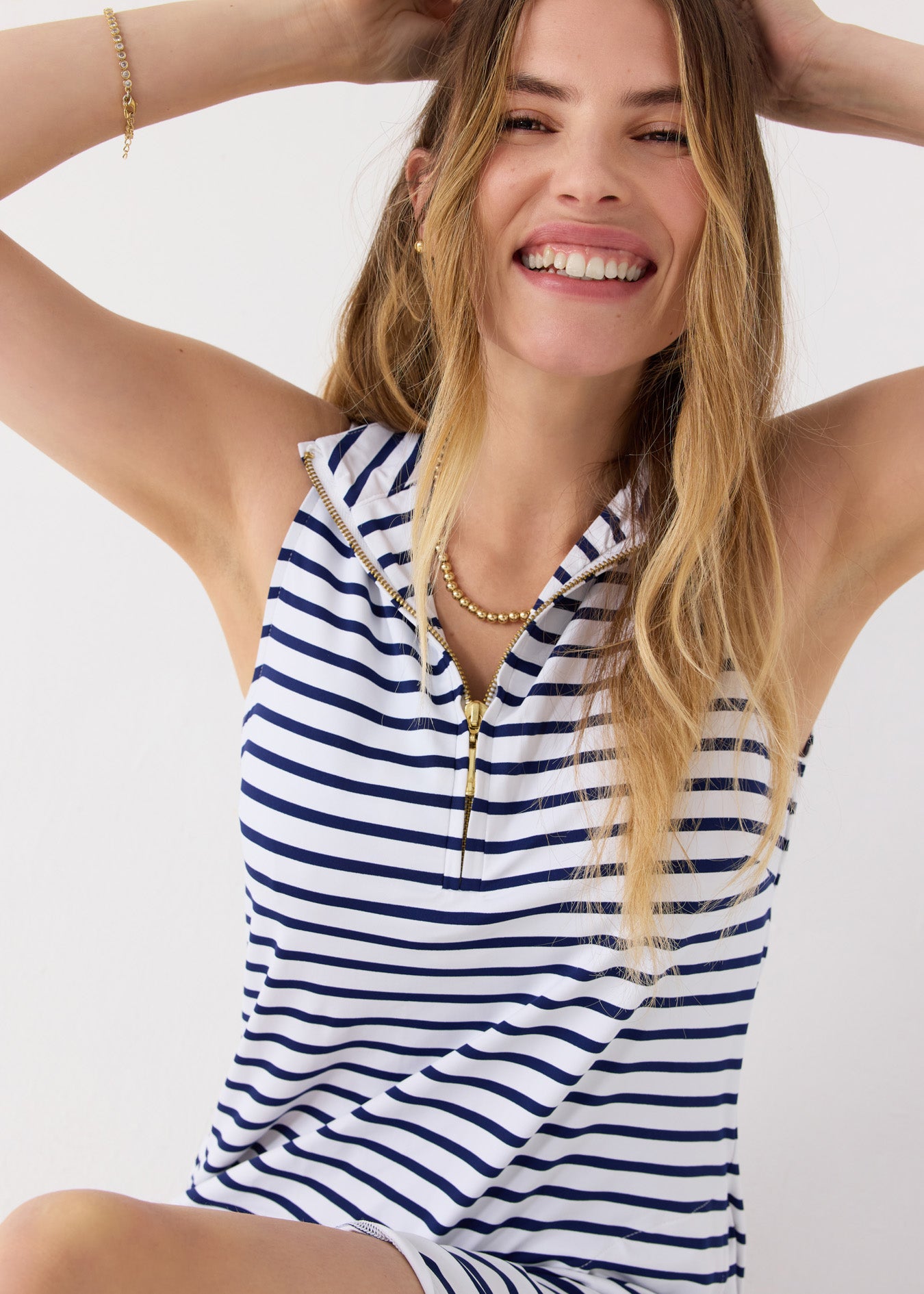 A blonde woman wearing the Cabana Life sun protective Navy Stripe 1/4 Zip Sleeveless Sport Dress with gold jewelry.