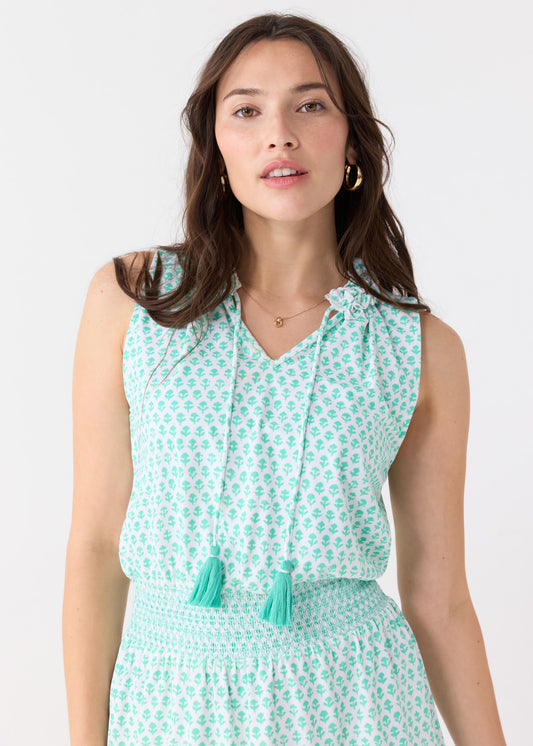 A close up of a brunette woman wearing the Cabana Life sun safe Rosemary Beach Smocked Waist Dress with gold hoop earrings.