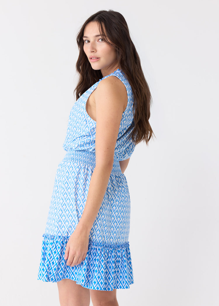 A dark-haired woman looking back wearing the Cabana Life sun safe Seaside Smocked Waist Dress.