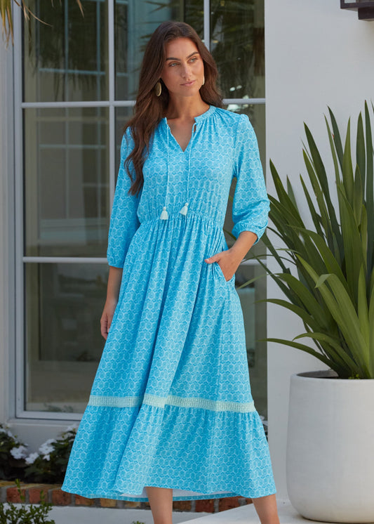 A brunette woman outside of a house with a hands in pocket of the flowy Cabana Life sun protective Rosemary Beach Relaxed Maxi Dress.