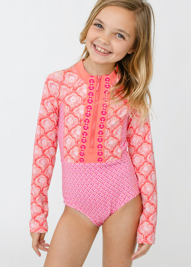 A blonde girl wearing the sun protective Girls Amelia Island Long Sleeve One-Piece from Cabana Life.