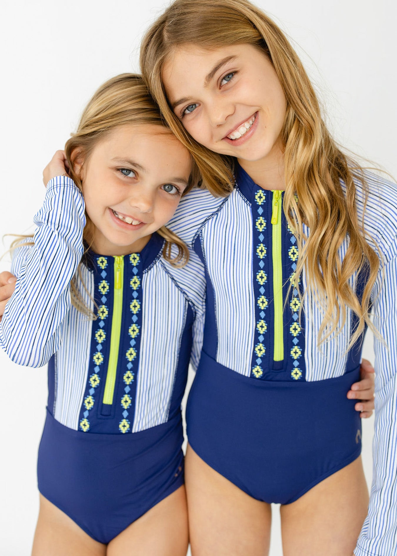 Blonde girls matching in Cabana Life's sun protective Girls Seaside Long Sleeve One-Piece.