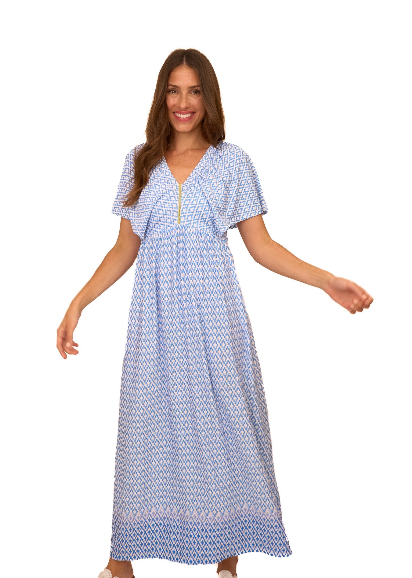 A brunette woman wearing the flowy Cabana Life sun protective Seaside Flutter Sleeve Maxi Dress on a white background.