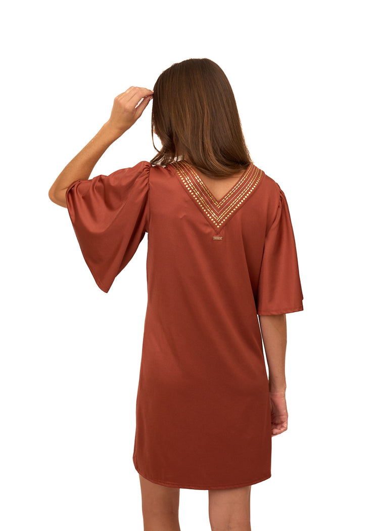 The back of a brunette woman wearing Cabana Life's sun protective Copper Flutter Sleeve Shift Dress with her arm up to her head on a white background.