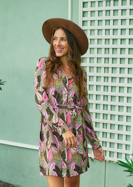 A brunette woman in front of a green building wearing a brown felt halt and Cabana Life's sun protective Myers Button Down Shirt Dress.