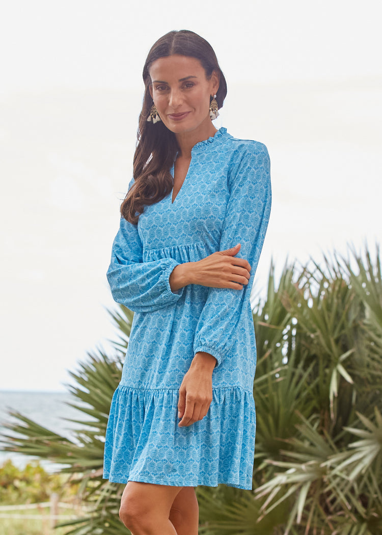 A brunette woman with an arm across her stomach wearing the Cabana Life sun protective Rosemary Beach Relaxed Dress outside.