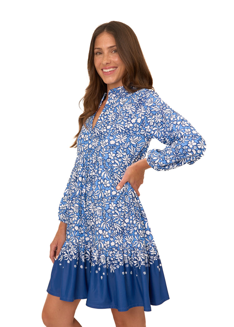 The side of a brunette woman with her hand on hip wearing Cabana Life's sun protective Seaside Floral Relaxed Dress on a white background.