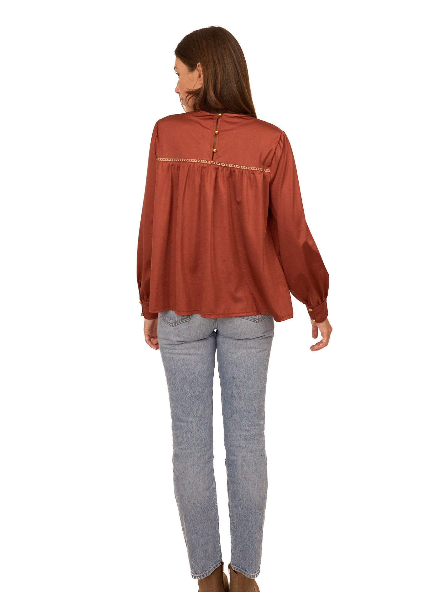 The back of a brunette woman wearing Cabana Life's sun protective Copper Long Sleeve Top with light wash jeans on a white background.