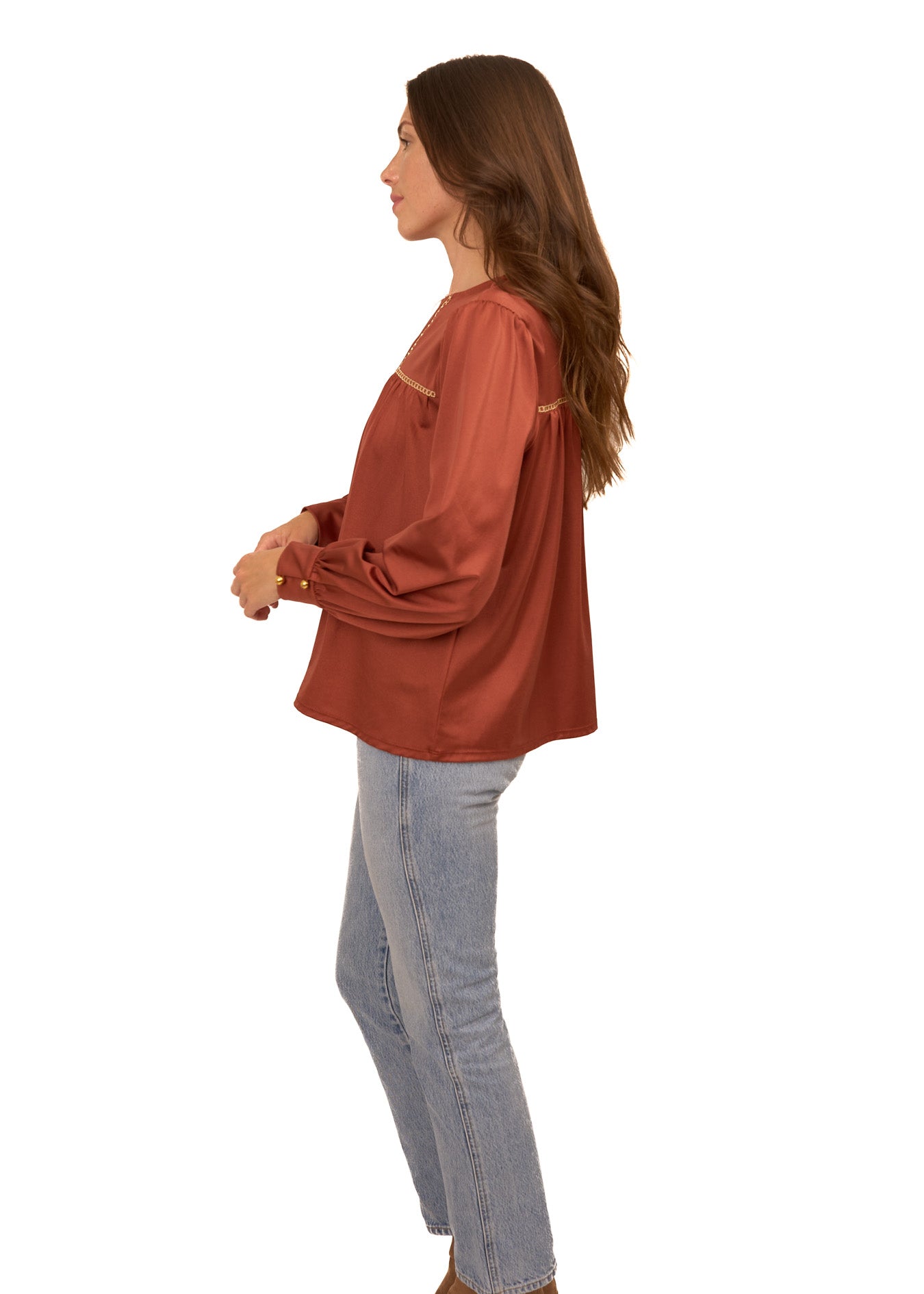 The side of a brunette woman wearing Cabana Life's sun protective Copper Long Sleeve Top with light wash jeans on a white background.