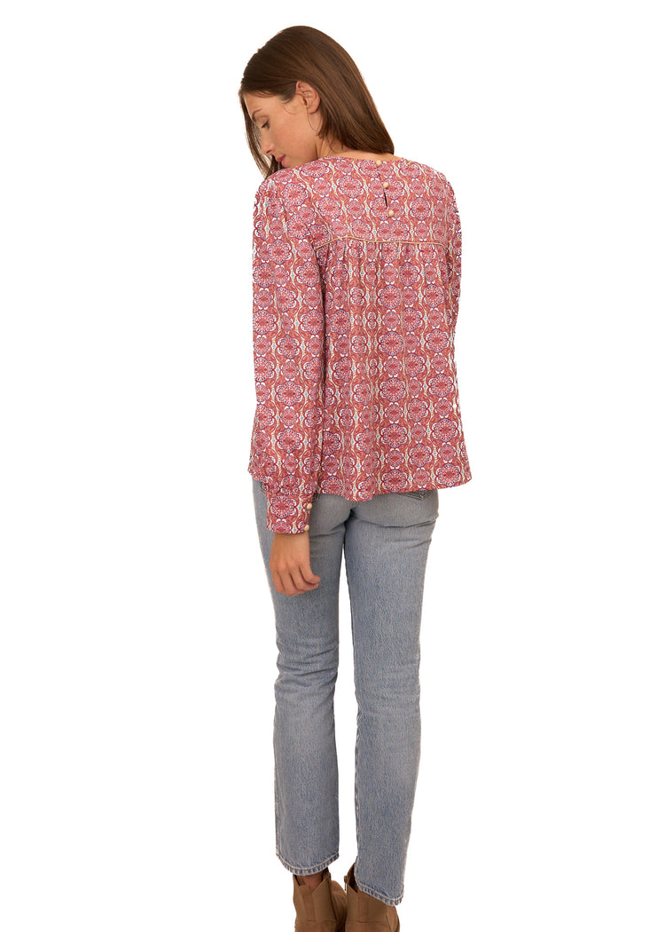 The back of a brunette woman wearing Cabana Life's sun protective Camden Geo Long Sleeve Top with light wash jeans on a white background.