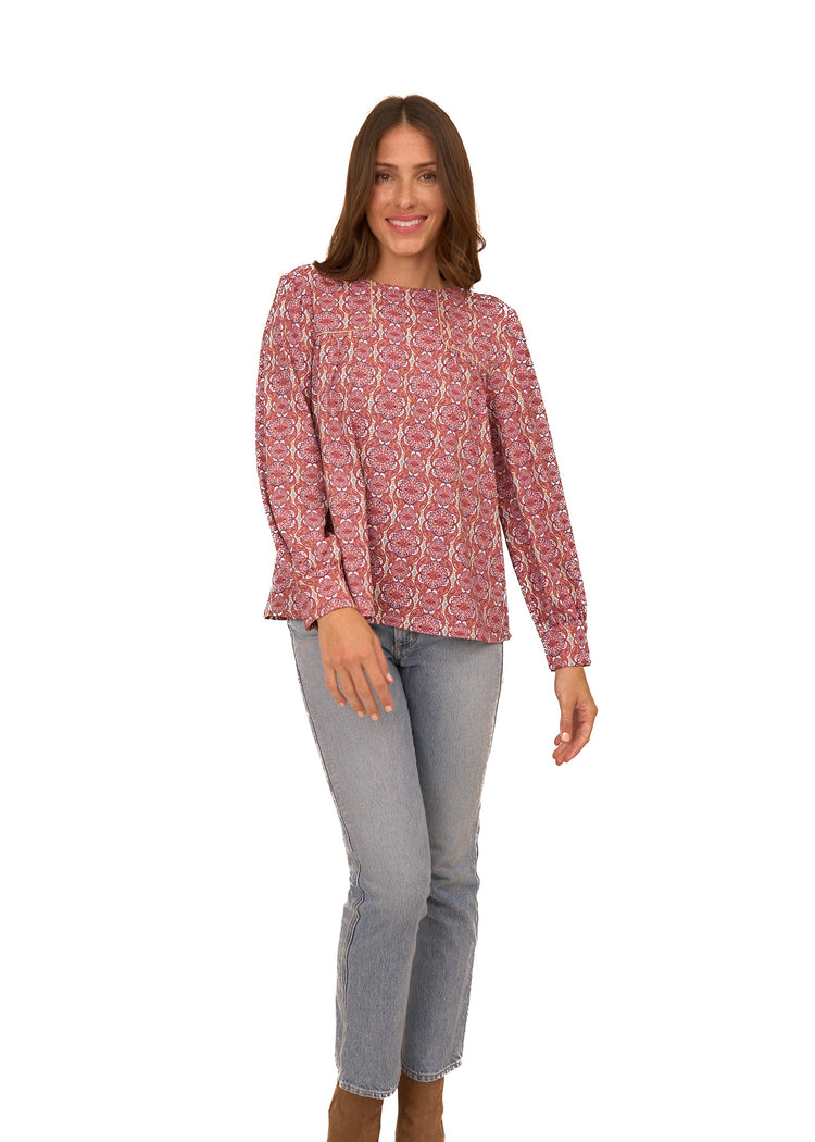 A brunette woman wearing Cabana Life's sun protective Camden Geo Long Sleeve Top with light wash jeans on a white background.