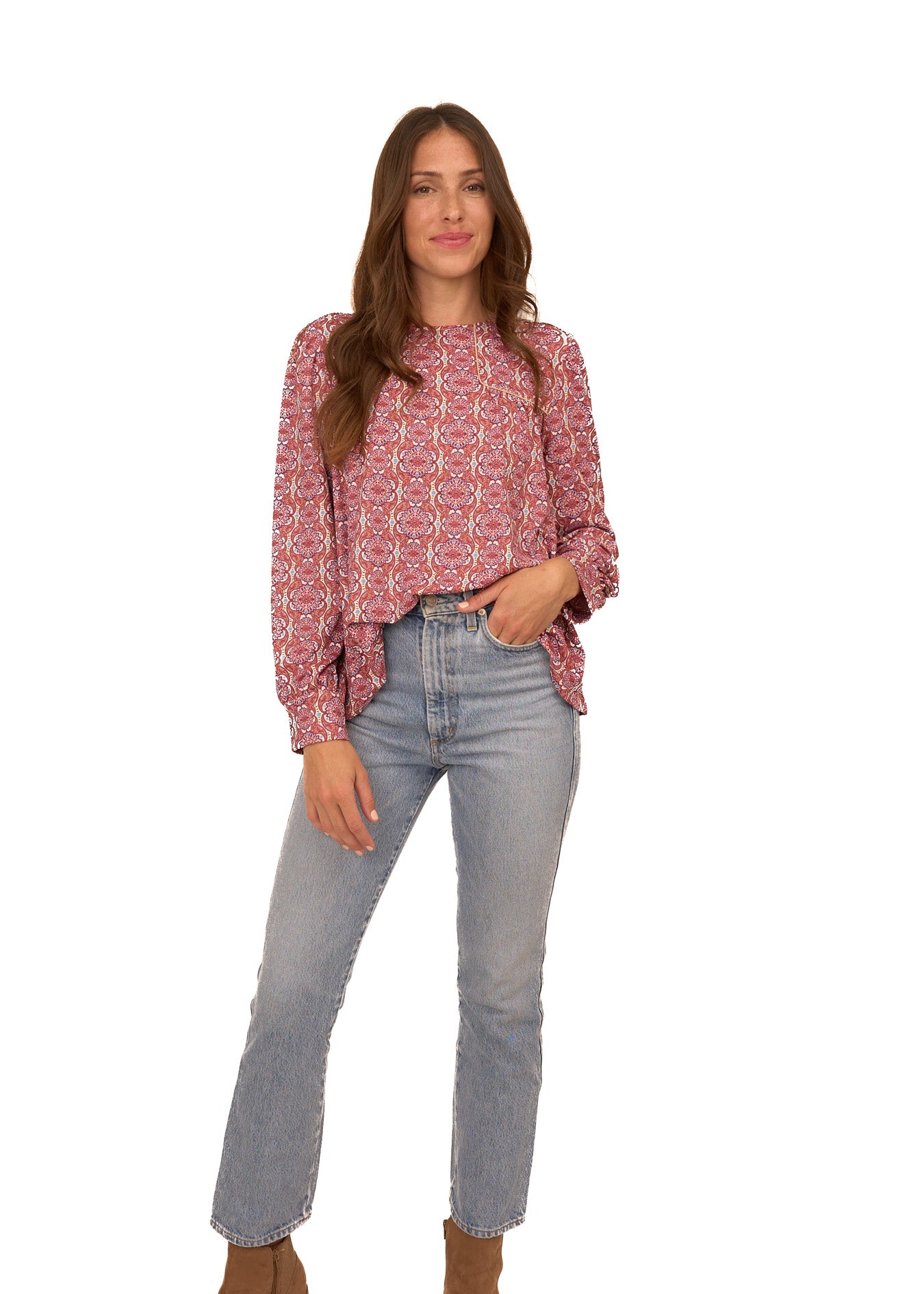 A brunette woman wearing Cabana Life's sun protective Camden Geo Long Sleeve Top tucked into light wash jeans on a white background.