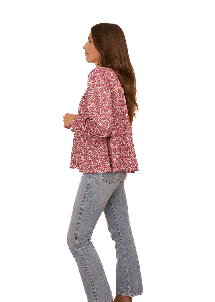 The side of a brunette woman wearing Cabana Life's sun protective Camden Geo Long Sleeve Top with light wash jeans on a white background.