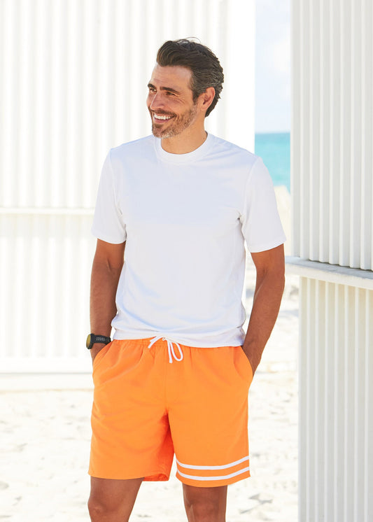 Man walking on beach wearing Cabana Life Men's White Short Sleeve Rashguard with Tangerine Swim Trunks