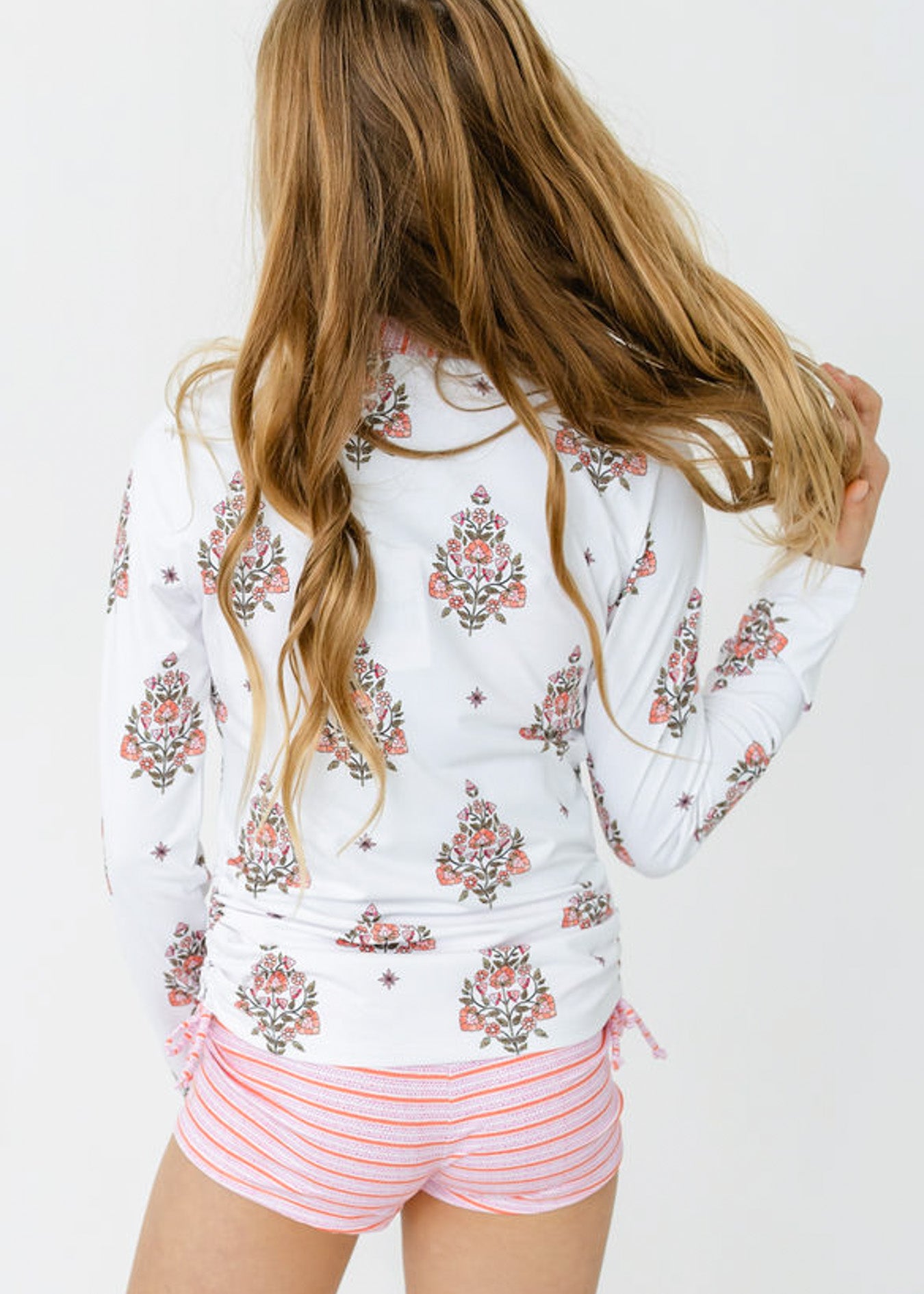 The back of a blonde girl wearing the sun protective Girls Amelia Island 3-Piece Long Sleeve Rashguard Set from Cabana Life.