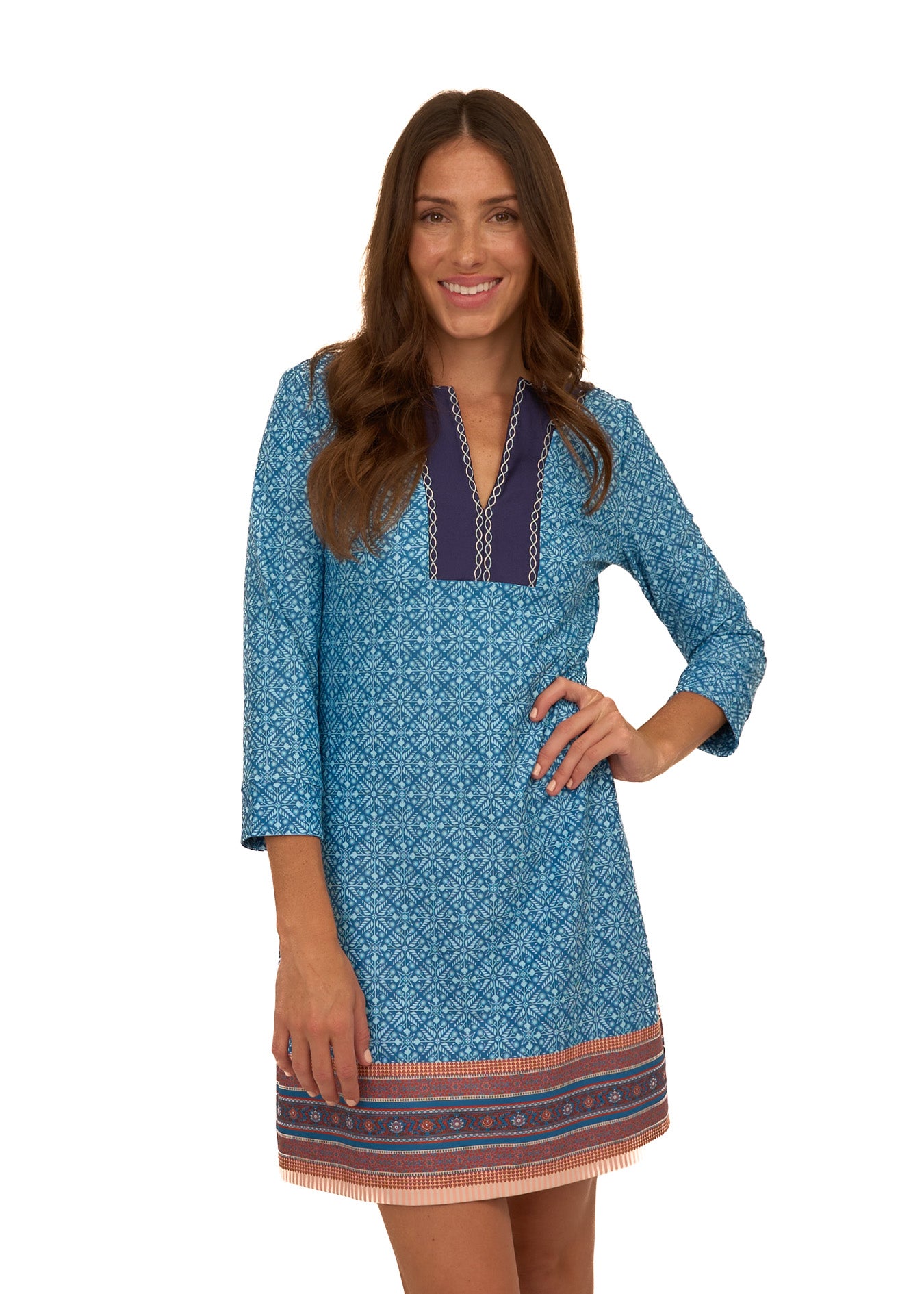 A brunette woman with her hand on her hip wearing Cabana Life's sun protective Camden Leaf Embroidered Tunic Dress on a white background.