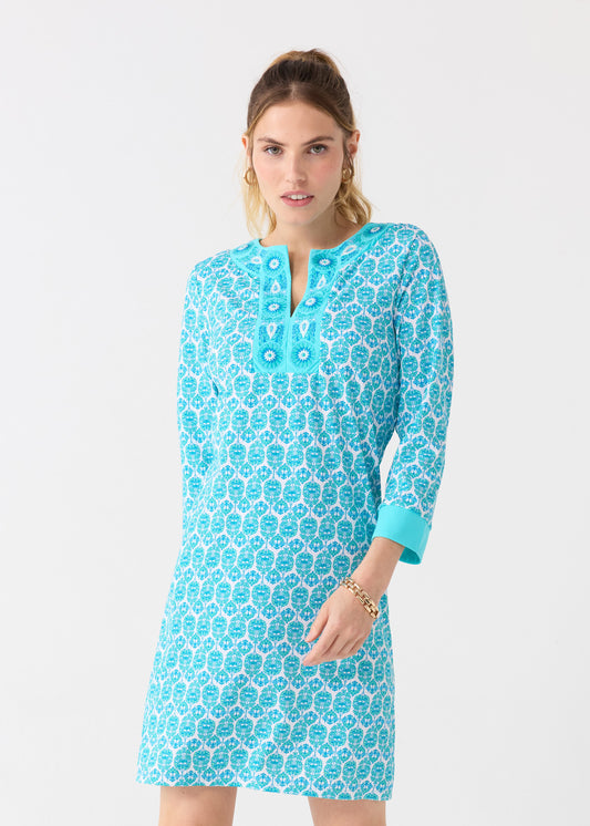 A woman with her hair up in a ponytail wearing the Cabana Life sun protective Rosemary Beach Embroidered Tunic Dress with gold jewelry.