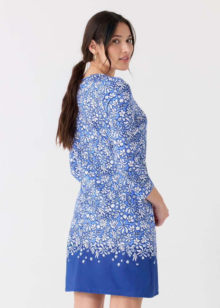 A dark haired woman looking back in the Cabana Life sun protective Seaside Floral Cabana Shift Dress.