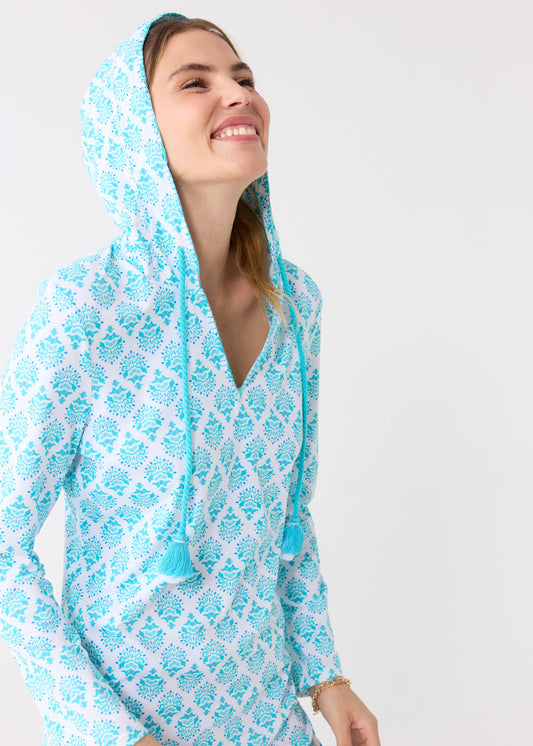 A blonde woman smiling while wearing the Cabana Life sun safe Amalfi Coast Hooded Cover Up with the hood on.