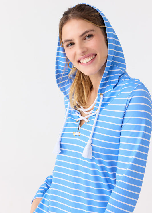 A close up of a blonde woman wearing the hood up on the Cabana Life sun protective striped Palm Beach Lace Up Hooded Cover Up.