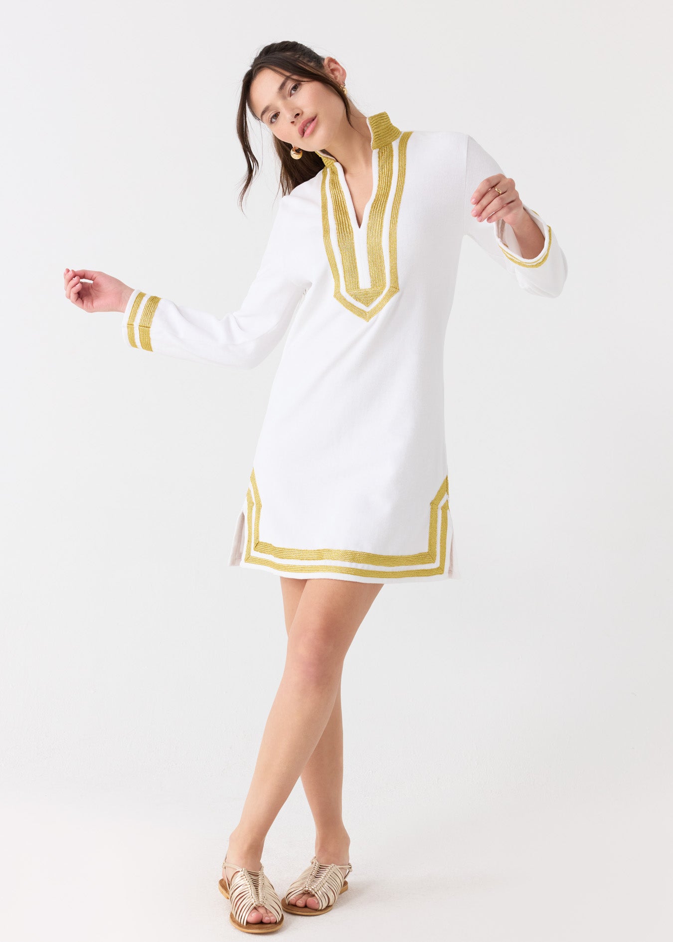 A woman dancing in the sun protective Cabana Life White/Gold Terry Tunic with gold sandals.