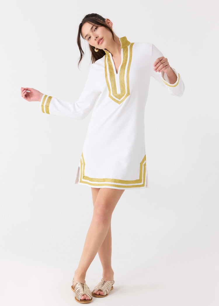 A woman dancing in the sun protective Cabana Life White/Gold Terry Tunic with gold sandals.