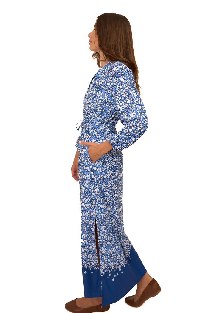 The side of a brunette woman wearing Cabana Life's sun protective Seaside Floral Button Down Maxi Dress with a hand in pocket on a white background.