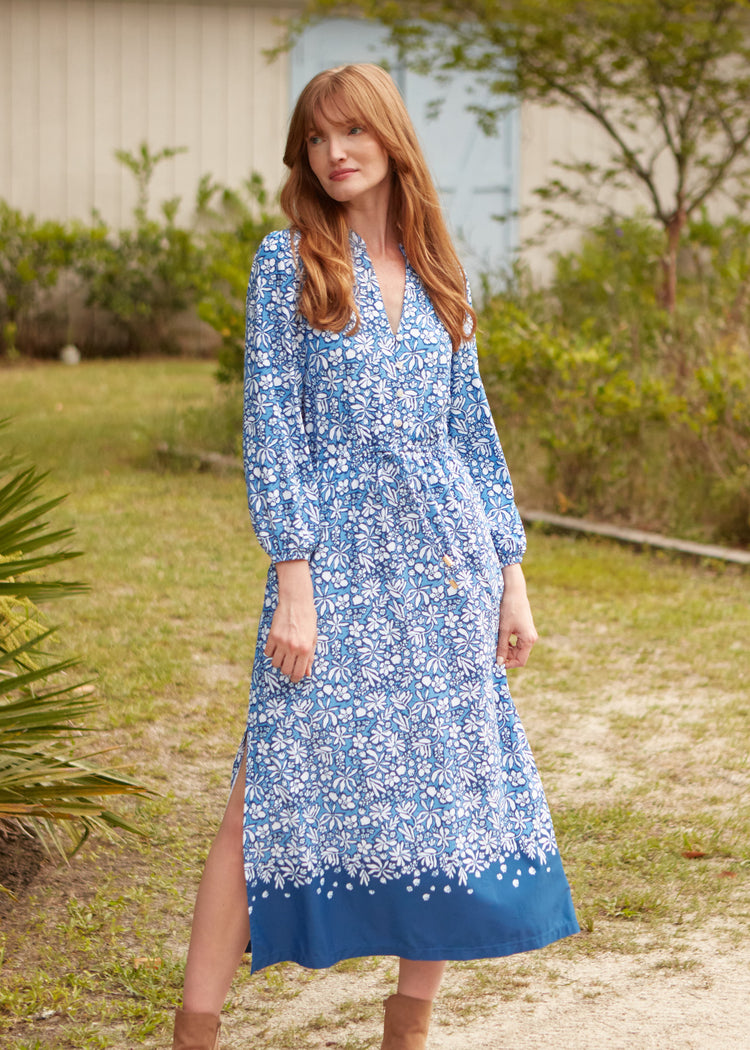 A redhead woman wearing the sun protective Cabana Life Seaside Floral Button Down Maxi Dress with leg sticking out of slit.