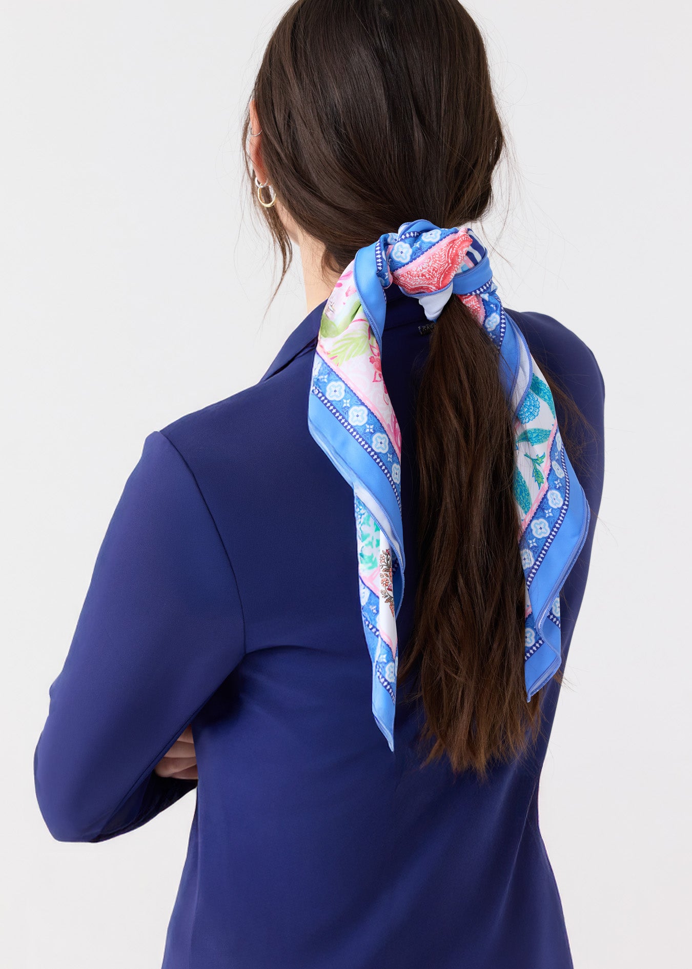 The back of a woman wearing the Cabana Life sun protective Navy 1/4 Zip Sport Top with a long brunette ponytail tied with the 2025 Printed Patchwork Scarf. 