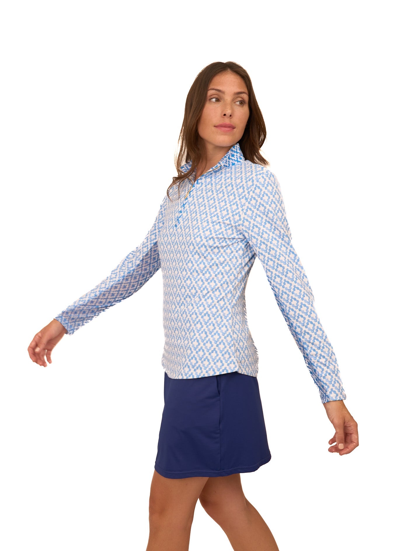 The side of a brunette woman walking wearing the Cabana Life sun protective Seaside 1/4 Zip Sport Top showing the mesh underarm and Navy 17" Skort on a white background.