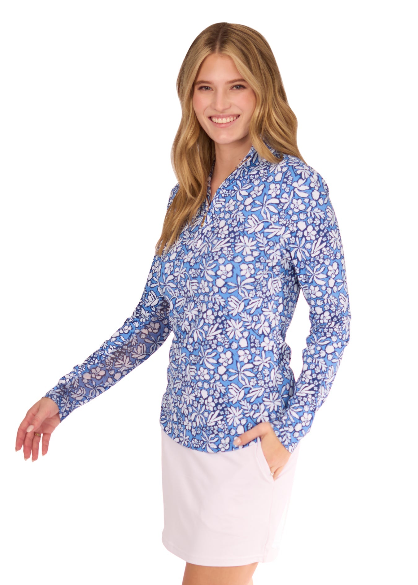 The side of a blonde woman wearing the sun protective & navy Seaside Floral 1/4 Zip Sport Top and White 14" Skort from Cabana Life on a white background.