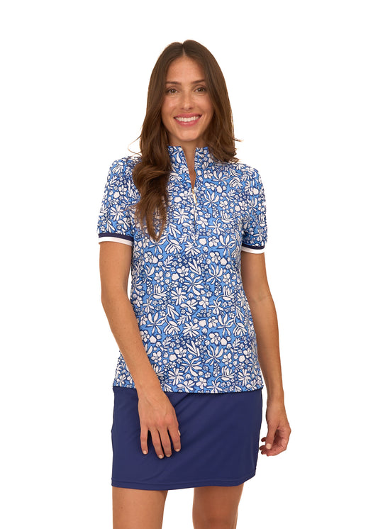 A brunette woman wearing the sun protective & navy floral Seaside Short Sleeve Collared 1/4 Zip and Navy Skort from Cabana Life on a white background.