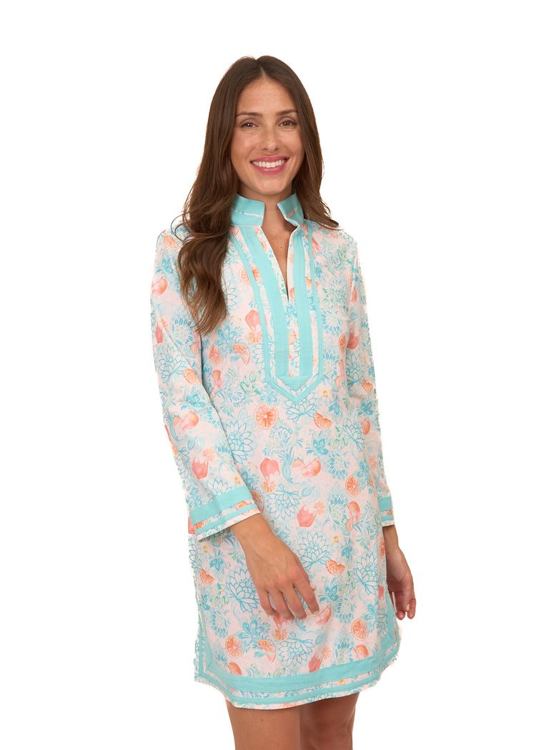 A brunette woman wearing Cabana Life's sun protective Spritz Tunic Dress on a white background.