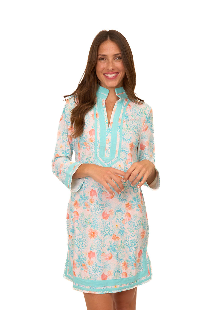 A brunette woman with her arms in front of her chest wearing Cabana Life's sun protective Spritz Tunic Dress on a white background.