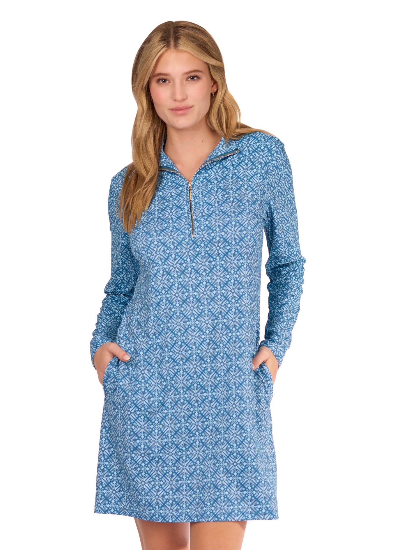 A blonde woman with hands in pockets wearing the sun protective and turquoise printed Camden 1/4 Zip Sport Dress from Cabana Life on a white background.