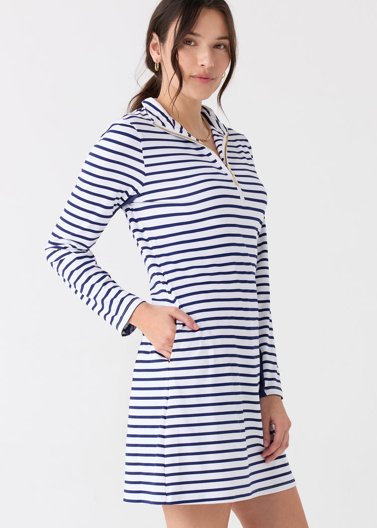 The side of a dark haired woman wearing the Cabana Life sun protective Navy Stripe 1/4 Zip Sport Dress with a hand in her pocket.