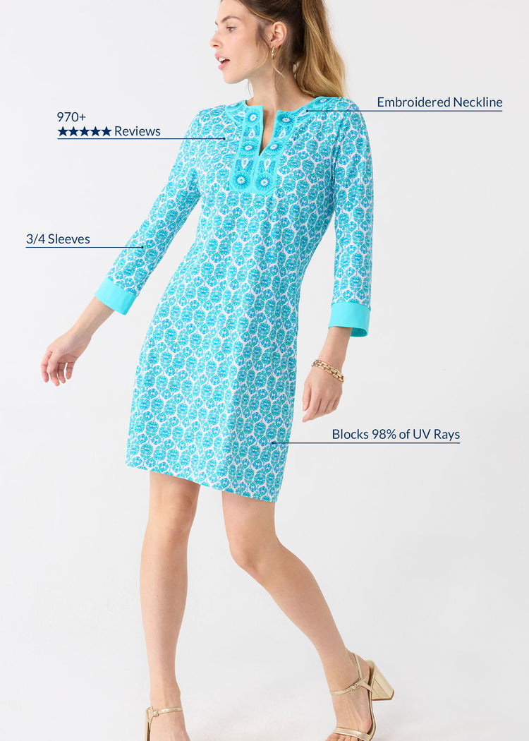 A woman with her hair up in a ponytail wearing the Cabana Life sun protective Rosemary Beach Embroidered Tunic Dress with gold jewelry and heels.