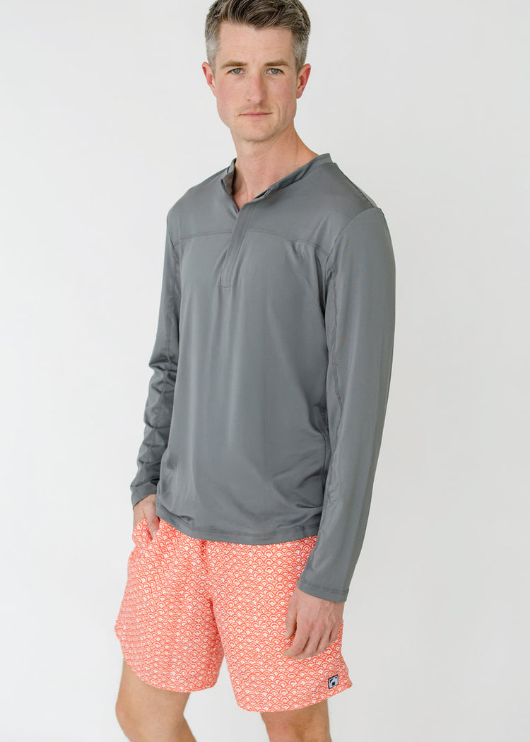 A man wearing the sun protective Men's Grey Sport Zip Top and the Men's Amelia Island Swim Trunk from Cabana Life.