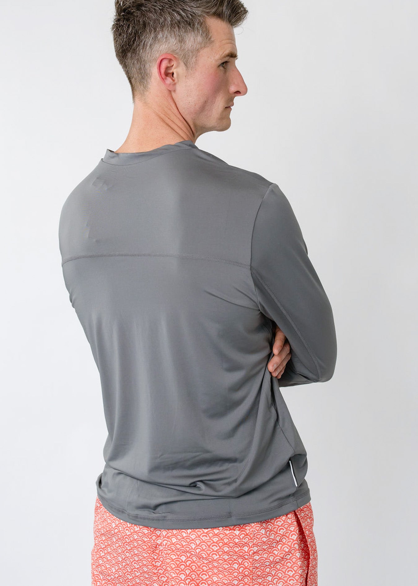 The back of a man wearing the sun protective Men's Grey Sport Zip Top and the Men's Amelia Island Swim Trunk from Cabana Life.