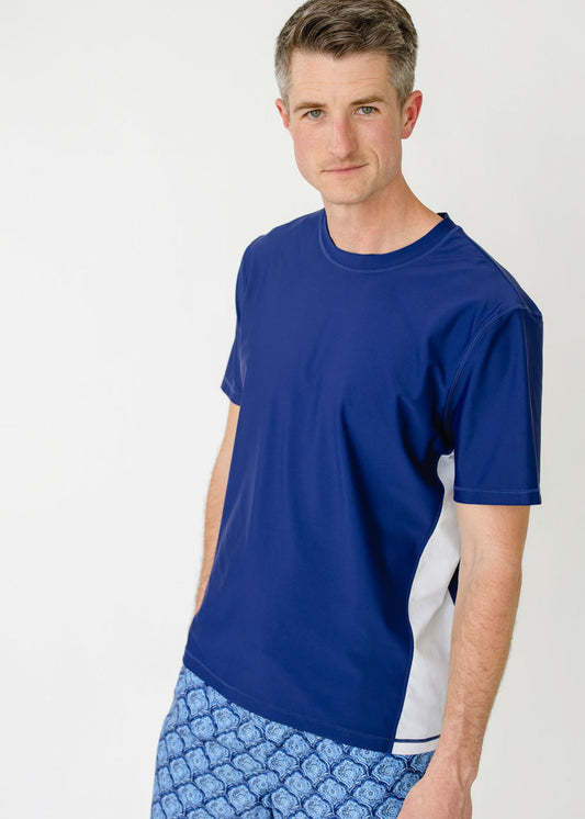 A man wearing the sun protective Men's Navy Short Sleeve Rashguard with the Men's Seaside Swim Trunk from Cabana Life.