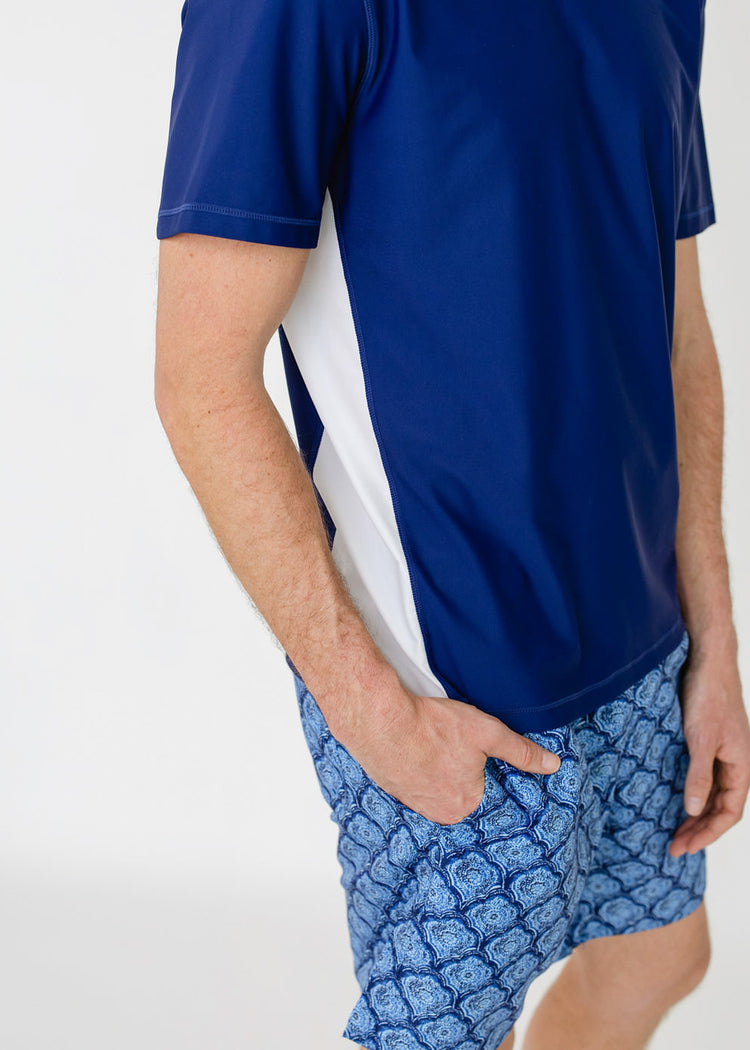 The side of a man wearing the sun protective Men's Navy Short Sleeve Rashguard with the Men's Seaside Swim Trunk from Cabana Life.