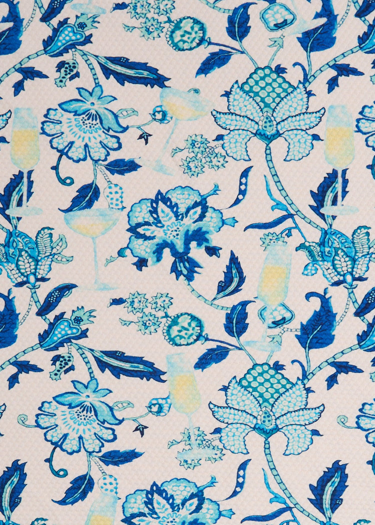 A close-up of Cabana Life's sun protective Bubbly print pique fabric featuring a blue floral print with champagne and white wine glasses.