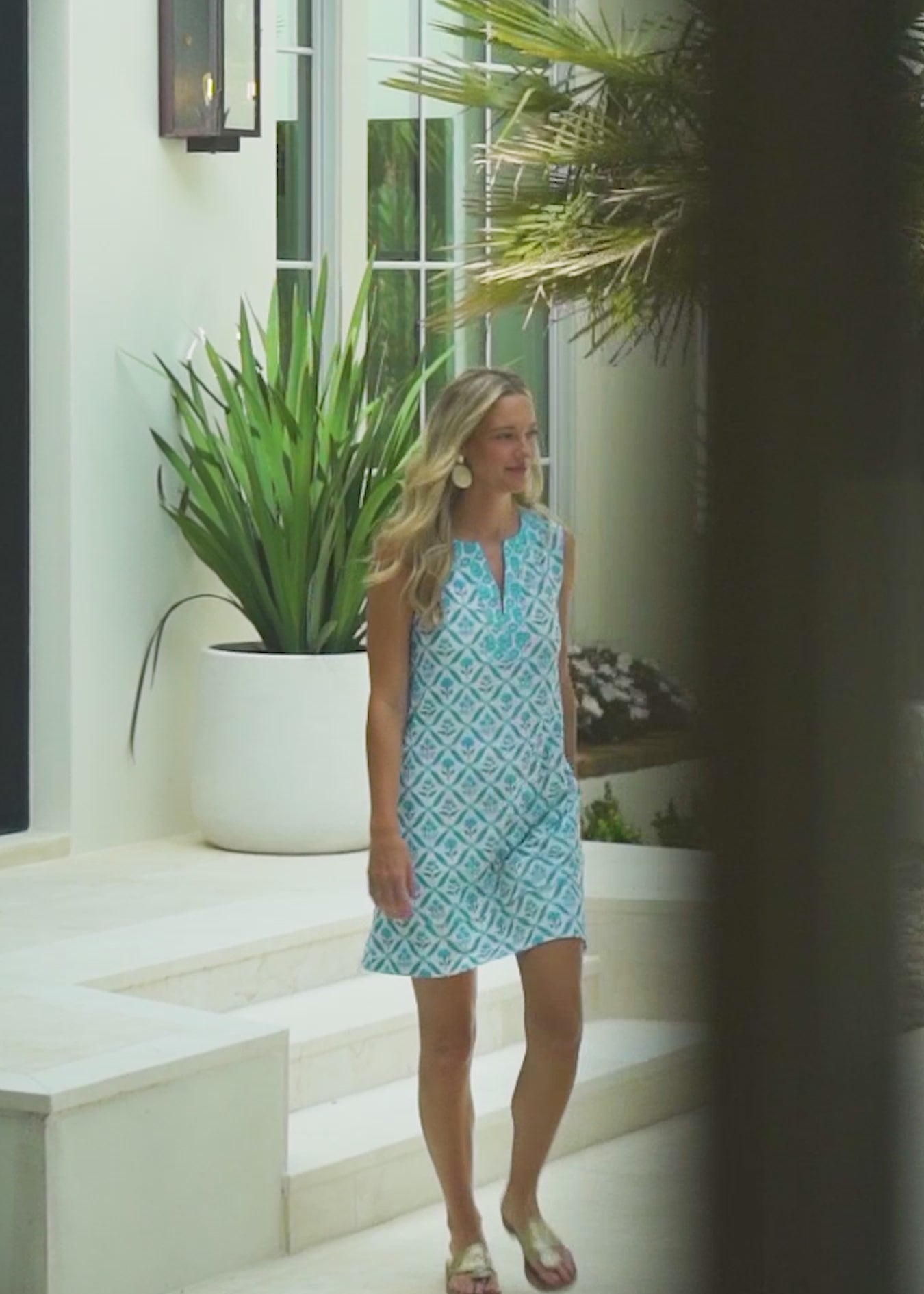 A blonde woman walking outside wearing the Cabana Life sun protective Rosemary Beach Sleeveless Tunic Dress.