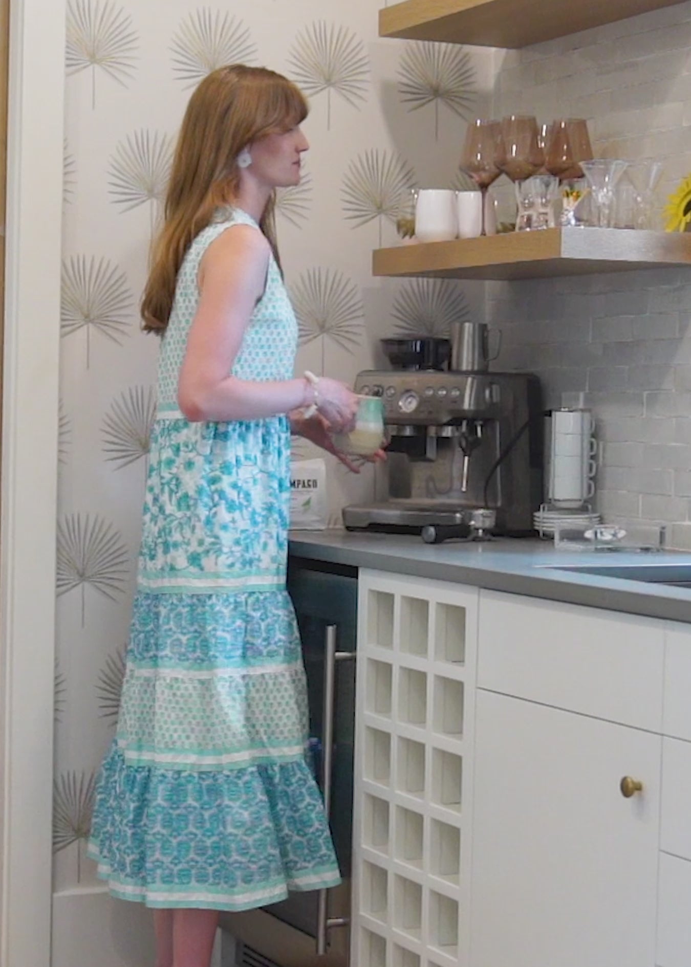 A redhead woman wearing the Cabana Life sun protective Rosemary Beach Sleeveless Tiered Maxi Dress inside a house.